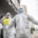 A volunteer disinfects a colleague outside a hotel where recovered patients spend a 14-day quarantine in Wuhan in China's central Hubei province